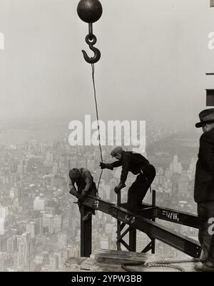 In cima all'Empire State Building, New York. 1930. Lavoratori in posizione precaria, al di sopra di New Work, che mettono in atto un beem rubato. Vedute delle condizioni di lavoro in America 1930s Photo Credit: Lewis Wickes Hine. Foto Stock