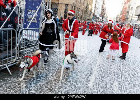 Liverpool, Regno Unito. 1 dicembre 2024. Una giovane coppia con cani partecipa al Liverpool Santa Dash 2024. I partecipanti indossati in rosso (e blu) Santa Suits corrono lungo un percorso di 5 km intorno al centro di Liverpool a sostegno del Claire House Children's Hospice. 8.500 persone hanno preso parte al 20 ° annuale Liverpool Santa Dash. (Credit Image: © Andy Von Pip/SOPA Images via ZUMA Press Wire) SOLO PER USO EDITORIALE! Non per USO commerciale! Foto Stock