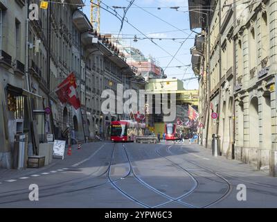 Situazione nel centro storico di Berna, Svizzera. Un tram e un tram che si spostano lungo una strada con vecchi edifici Foto Stock