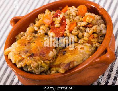 Cosce di pollo con porridge di orzo in pentola di argilla Foto Stock