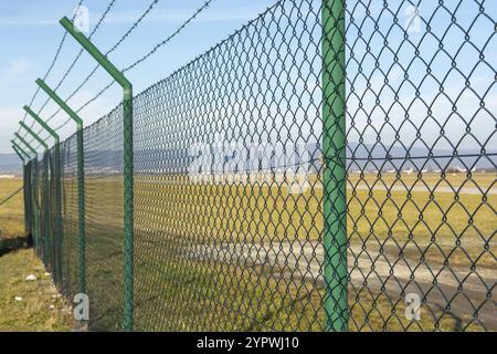 Recinzione in rete metallica verde intorno all'area dell'aeroporto. Protezione dell'area limitata Foto Stock