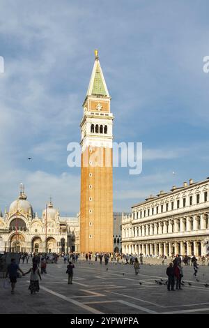 Piazza San Marco a Venezia, in Italia, in un bellissimo tardo pomeriggio. Campanile San Marco alla luce del sole, molta gente e colombe sulla piazza e sullo storico Foto Stock