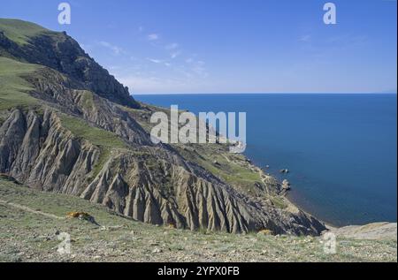 Tracce di erosione del suolo e agenti atmosferici sul ripido pendio di Capo Meganom di fronte al mare. Crimea, una giornata di sole ad aprile Foto Stock