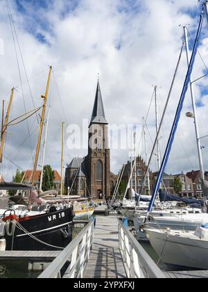 Harlingen, Paesi Bassi, ha una splendida città vecchia con un bacino portuale. Vista sulle barche a vela ormeggiate verso la chiesa della città Foto Stock