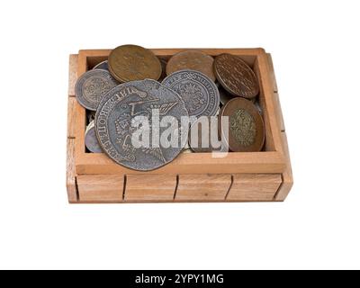 Tesoro di antiche monete in una cassa di legno isolata sul bianco. Vecchio denaro metallico di diversi paesi nella confezione. Salvadanaio di monete dal circul Foto Stock