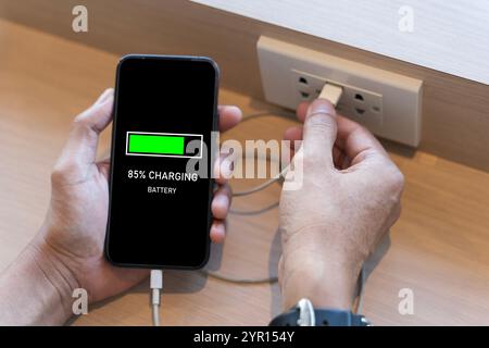 Primo piano sulla batteria di ricarica dello smartphone mobile. Batteria di ricarica del telefono cellulare. Uomo che tiene in mano lo smartphone e ricarica la batteria dalla presa usb integrata o Foto Stock