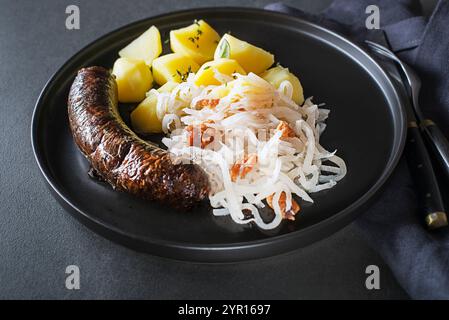 Morcilla di salsiccia sanguinosa, rapa acida stufata e patate da vicino. Piatto tradizionale sloveno con salsiccia arrosto Foto Stock