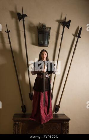 Giovane donna che rievoca un cavaliere medievale con una tunica in pelle e un'armatura in metallo nello stile di Giovanna d'Arco Foto Stock