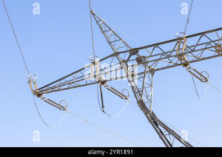 Struttura metallica di pilone elettrico che supporta i cavi di alimentazione ad alta tensione contro un cielo blu brillante Foto Stock