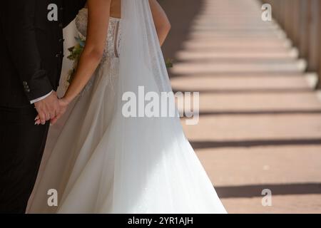 Coppia di sposi che si tengono per mano, camminano lungo il corridoio dopo la cerimonia di nozze, cominciano la loro nuova vita insieme Foto Stock