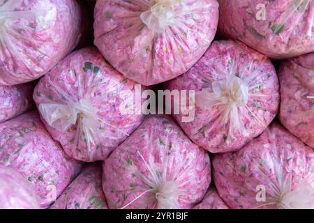 Molti sacchi di plastica con fiori raccolti di rose varietà Damascena su un mucchio nel magazzino della distilleria Foto Stock