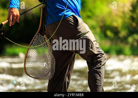 L'uomo tiene la rete e la canna da pesca con la mosca Foto Stock