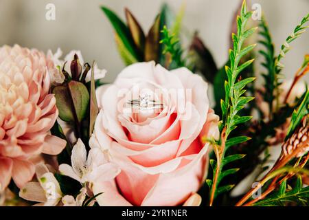 Foto macro delle fedi nuziali sedute su una rosa rosa Foto Stock