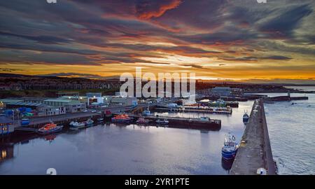 Buckie Harbour Moray Coast Scozia un vivace tramonto invernale con scialuppe di salvataggio ormeggiate e barche da pesca Foto Stock