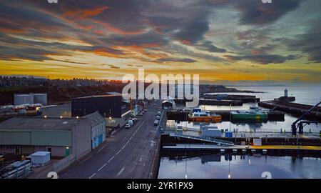 Buckie Harbour Moray Coast Scozia inverno una variopinta turbina eolica ormeggiata al tramonto navi di supporto e un nuovo edificio Ocean Wave Foto Stock