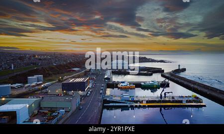 Buckie Harbour Moray Coast Scozia, navi di supporto per turbine eoliche ormeggiate al tramonto e nuovo edificio Ocean Wave Foto Stock