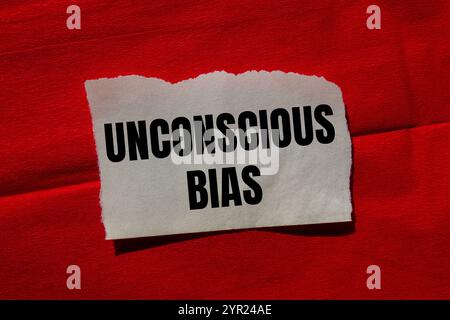 Messaggio di bias inconscio scritto su un pezzo di carta strappato su sfondo rosso. Simbolo di pregiudizio inconscio concettuale. Copia spazio. Foto Stock
