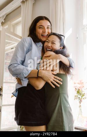 Donna felice che abbraccia un'amica mentre sta a casa Foto Stock