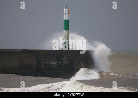 Aberystwyth Galles Regno Unito tempo 2 dicembre 2024. Una fredda e blustera mattinata invernale intorno alla costa gallese, grandi onde si infrangono sulle difese del mare e la luce del porto con cieli rosa sopra la testa, credito: mike davies/Alamy Live News Foto Stock