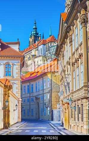 La fila di edifici storici in via Valdstejnska con la facciata del Senato ceco, il campanile e le guglie della Cattedrale di San Vito, che si innalzano sopra Foto Stock