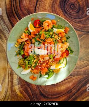 Piatto da pranzo decorativo con insalata con ingredienti come gamberi e verdure biologiche come lattuga di foglie di quercia, foglie di rucola e pomodoro Foto Stock