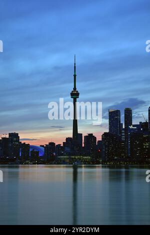 Le luci della città iniziano ad accendersi quando il sole tramonta dietro i grattacieli nel centro di Toronto, Canada. Foto Stock