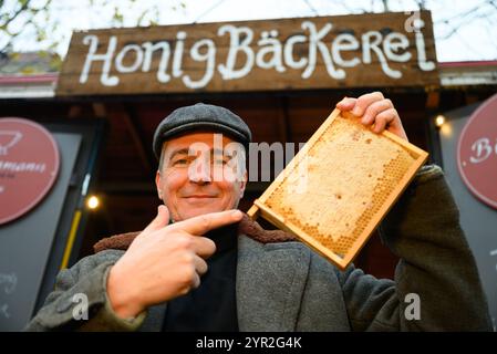 Dresda, Germania. 2 dicembre 2024. L'apicoltore Rico Heinzig tiene in mano un favo al suo stand presso lo storico mercatino di Natale di Neumarkt. Crediti: Robert Michael/dpa/Alamy Live News Foto Stock