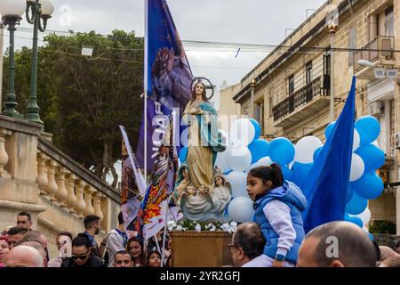 Cospicua, Malta - 1 dicembre 2024. Processione religiosa festiva che celebra il Santo con bandiere e palloncini all'aperto Foto Stock