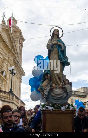 Cospicua, Malta - 1 dicembre 2024. Processione religiosa che celebra la Vergine Maria con palloni blu e folla Foto Stock