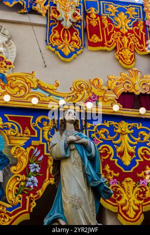 Cospicua, Malta - 1 dicembre 2024. Festa religiosa colorata processione con decorazioni ornate e partecipanti Foto Stock