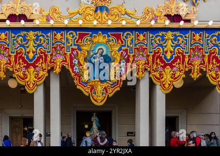 Cospicua, Malta - 1 dicembre 2024. Festa religiosa colorata processione con decorazioni ornate e partecipanti Foto Stock