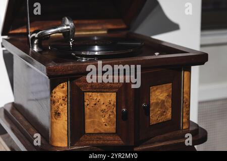 Fonografo vintage con corpo in legno e disco in vinile nero riproduce una vecchia musica, foto ravvicinate con una messa a fuoco morbida e selettiva Foto Stock