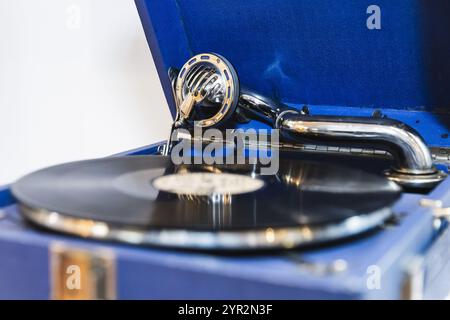 Fonografo blu vintage con disco in vinile nero riproduce una vecchia musica, foto ravvicinate con una messa a fuoco morbida e selettiva Foto Stock