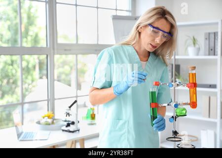 Scienziata donna con matracci di campioni di girasole che lavorano in laboratorio Foto Stock