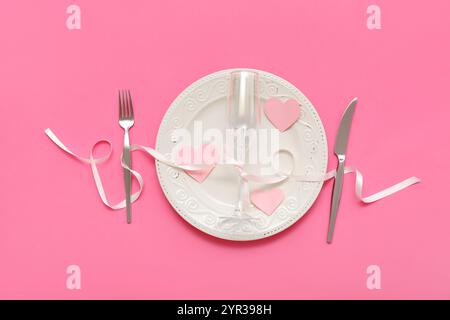 Tavolo per San Valentino con cuori di carta e nastro su sfondo rosa Foto Stock