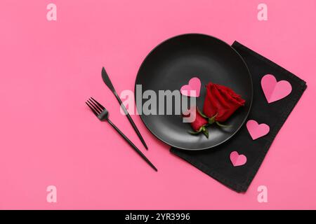 Tavolo per San Valentino con rose e cuori di carta su sfondo rosa Foto Stock