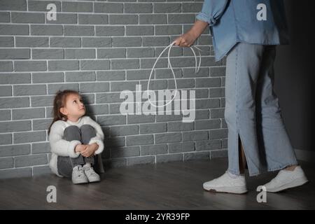 La bambina spaventata e sua madre con il filo vicino al muro di mattoni grigi. Concetto di violenza domestica Foto Stock