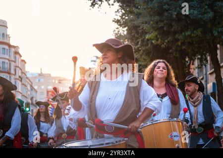 L'immagine cattura un gruppo di persone che partecipano a quella che sembra essere una sfilata o un festival di strada. Sono vestiti con costumi che hanno un Foto Stock