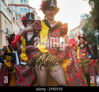 L'immagine mostra un gruppo di persone vestite con costumi colorati e coordinati, caratterizzati da un motivo tartan a quadri. Indossano cappelli, sono luminosi Foto Stock