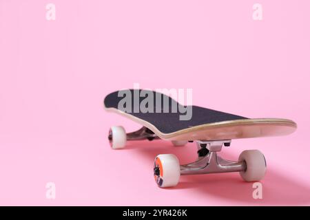 Uno skateboard su sfondo rosa, primo piano. Spazio per il testo Foto Stock