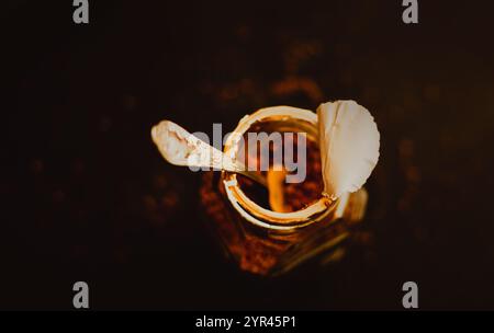 Vista dall'alto di un recipiente di caffè solubile forte con un cucchiaio argentato su uno sfondo scuro, per la colazione. L'amore per il caffè la mattina. Foto Stock