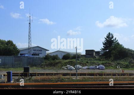 Portsmouth, Hampshire, Inghilterra. 26 agosto 2024. Borse accanto alla linea ferroviaria di Portsmouth, viste da una finestra del treno, con locali commerciali e un albero radio. Foto Stock