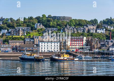 Porto e lungomare di Oban, con la Torre McCaig su Battery Hill che si affaccia sulla città, a Oban, Argyll e Bute, Scozia, Regno Unito Foto Stock