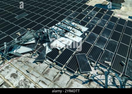 Vista dall'alto dei pannelli solari fotovoltaici distrutti dall'uragano Ian montati sul tetto di un edificio industriale per la produzione di elettricità ecologica verde Foto Stock