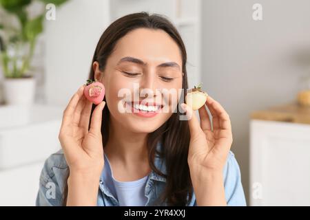 Bella giovane donna con fragole ricoperte di cioccolato in cucina Foto Stock