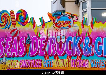 Vistosi negozi sul lungomare di Bridlington, East Yorkshire, con vivaci cartelli per negozi di dolci, gelaterie e divertimenti. Foto Stock