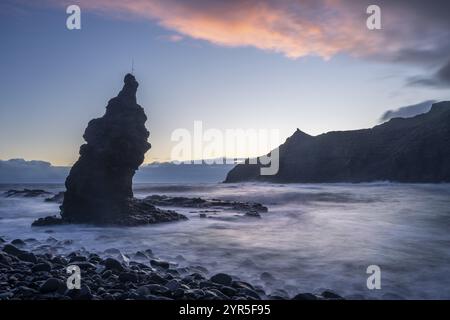 Alba sulla spiaggia di Playa de la Caleta con Punta San Lorenzo. Rocce e mare. Nuvole colorate nel cielo. Esposizione lunga. La Gomera, Isole Canarie Foto Stock