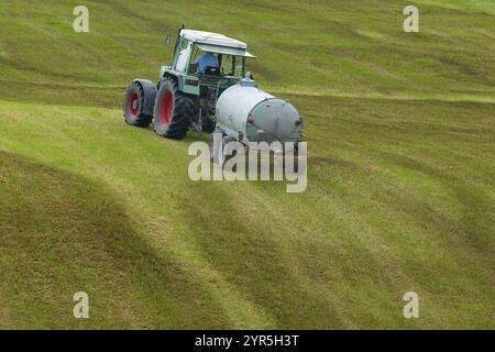 Trattore per lo spandimento di concime liquido su un terreno verde, prato, Baviera, Germania, Europa Foto Stock