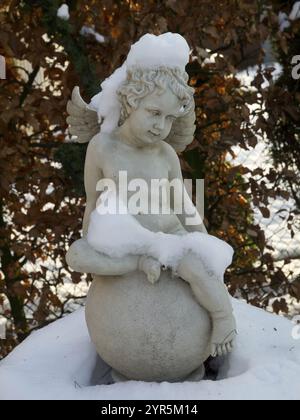 Angelo di marmo con copertura neve, incastonato in un paesaggio naturale invernale, borken, muensterland, germania Foto Stock