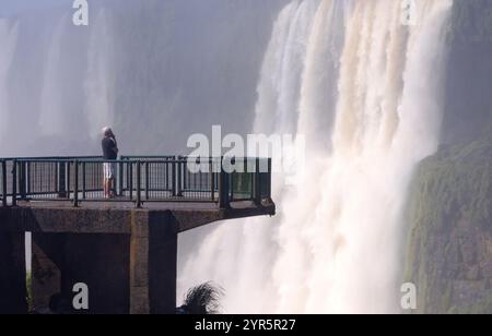 Un uomo in piedi sul lato brasiliano delle cascate Iguazu. Foto atmosferica della cascata e della forza della natura dell'acqua; Brasile Sud America Foto Stock